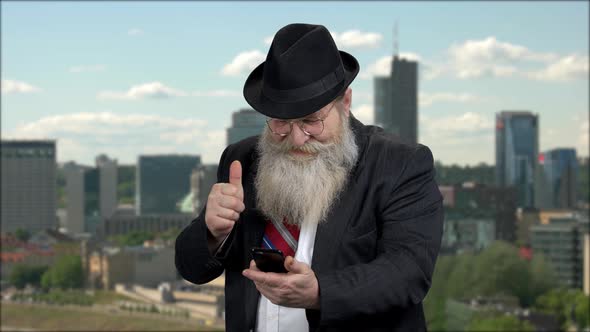 Mature Man Showing Thumb Up While Using Cell Phone