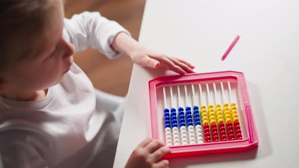 Smart Girl Pours Beads and Puts Stick to Abacus at Lesson