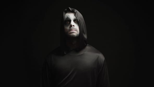 Young Man Dressed Up Like Grim Reaper Over Black Background