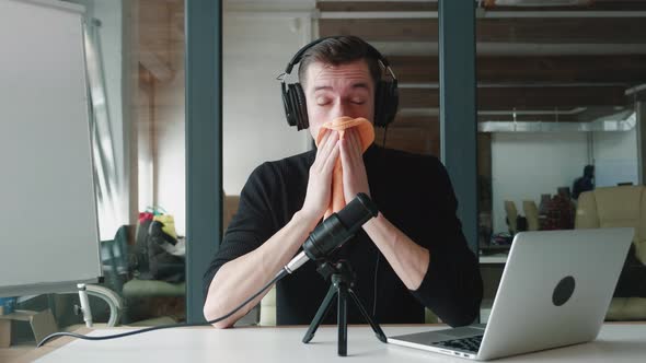 Young Man Blogger Sneezes and Blows His Nose While Recording Video Blog in Office