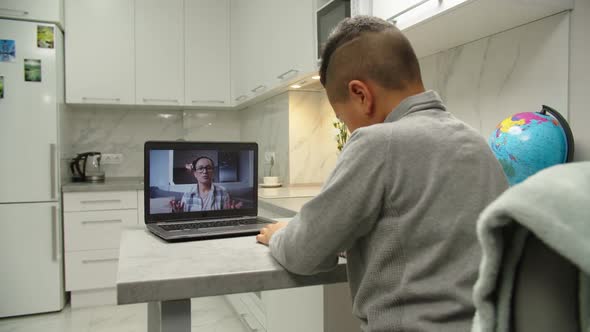 Preteen School Boy Listening Teacher Via Internet on Laptop at Home
