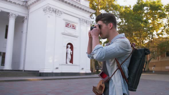 Attractive Young Handsome Man Tourist with Backpack Walking in City Center and Taking Photos on