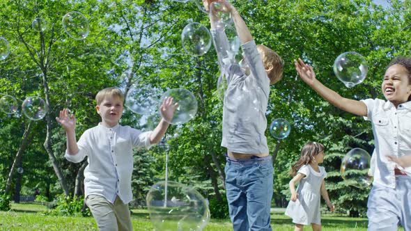 Cheerful Kids Chasing Soap Bubbles