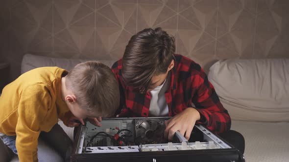 Young Man Repairing a Computer at Home with His Younger Brother