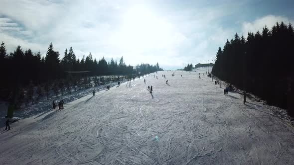 Aerial panoramic view of Topolita Snow summit with people snoboarding and skiing down slope while dr