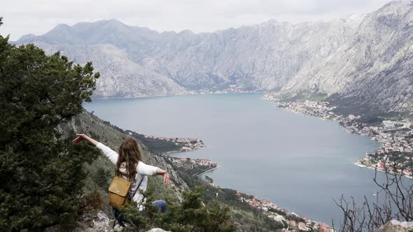 A Girl with a Backpack Sits on Top of a Mountain in Montenegro