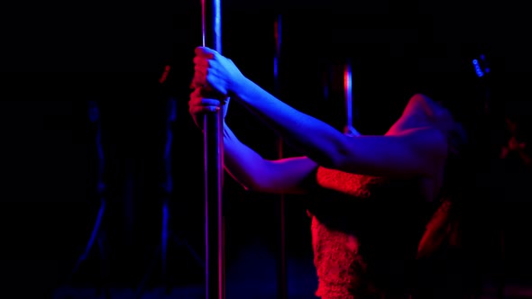 A Flexible Dancer Dances on a Pole Under the Light of Colorful Spotlights