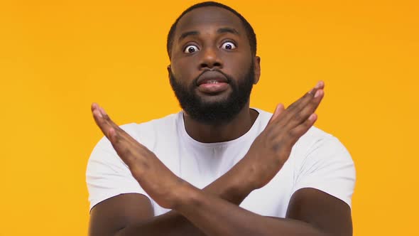Emotional Afro-American Male Crossing Hands, Warning Gesture, Yellow Background