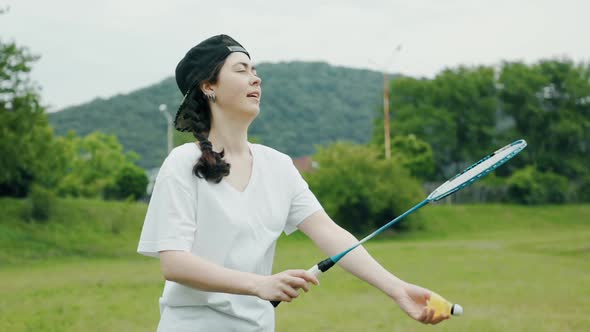 A Caucasian young pretty woman playing funny at badminton. Slow motion. Summer recreation concept.