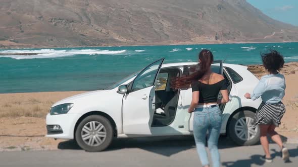 Two Girls Running to a Car at the Beach