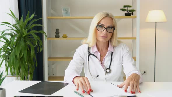 Senior European Woman Doctor Wearing White Medical Coat and Stethoscope Looking at Camera