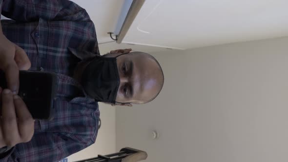 Adult Male Wearing Face Mask Checking Mobile Sitting Down On Stairwell. Low Angle, Vertical Video, L