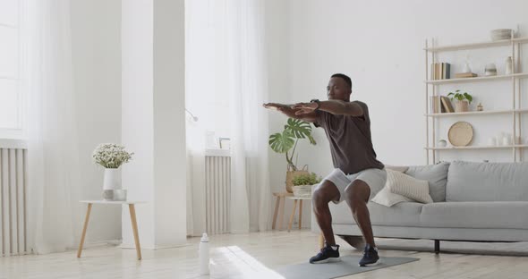 Home Workout. Young Sporty African American Man Doing Squats Exercises, Sports Training Alone