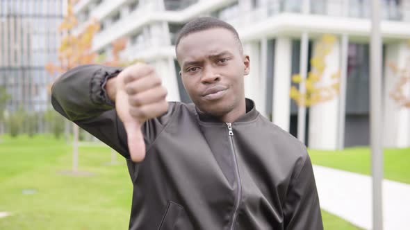 A Young Black Man Shows a Thumb Down To the Camera and Shakes His Head - Office Buildings