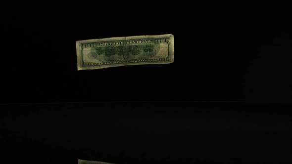 American $100 Bills Falling onto a Reflective Surface