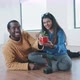 Young couple moving into new home sitting on the floor holding plant and drill - VideoHive Item for Sale