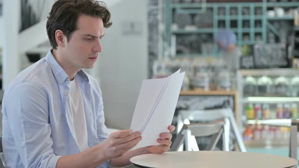 Young Man Celebrating Success While Reading Documents