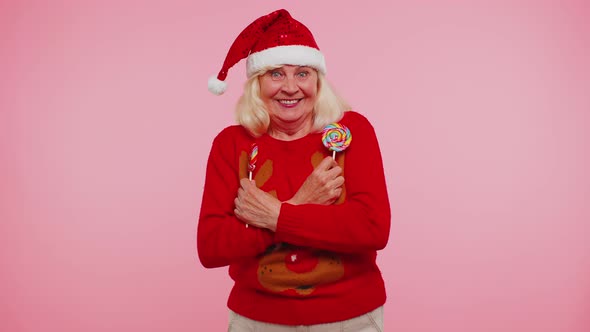 Senior Grandmother in Christmas Sweater Holding Candy Striped Lollipops Dancing Making Silly Faces