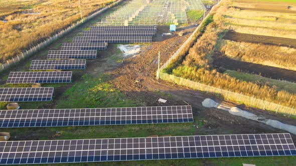 Aerial view of solar power plant under construction on green field. Assembling of electric