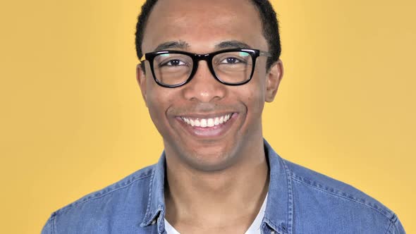 Close Up of Smiling African Man in Glasses Yellow Background