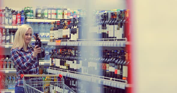 Woman Chooses Wine in the Supermarket