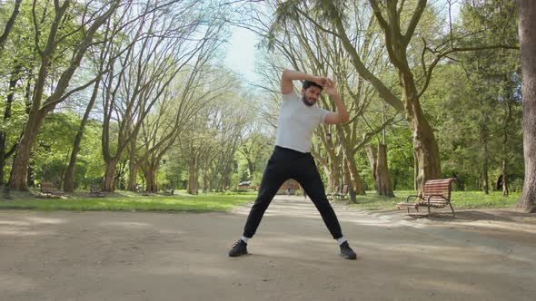 Healthy Muslim Guy in Sport Outfit Doing Flexible Exercises Outdoors