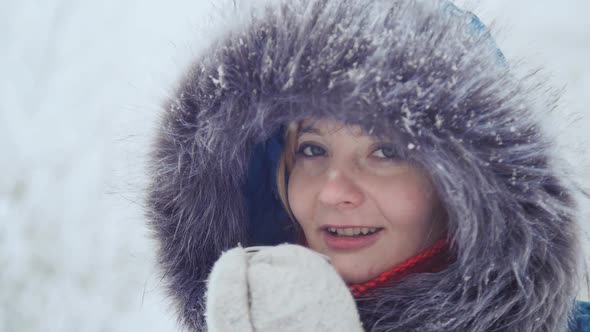 A Nice Girl in Mittens Drinks and Warms Herself with Hot Tea in a Winter Park