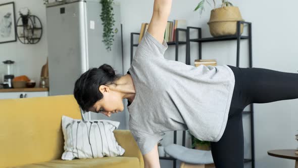 A Young Indian Woman Does Yoga Meditation At Home, Does A Balance Exercise