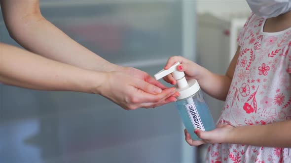 Little Girl Applying Antiseptic on Hands of Mom