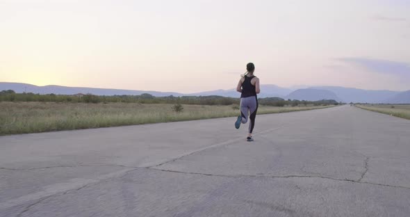 Determined Sporty Woman Running Trail Alone on the Road and Preparing for a Marathon