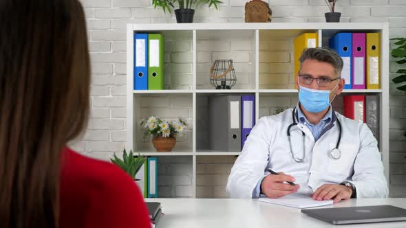 Doctor in protective medical mask, diagnoses patient, write symptoms in notebook