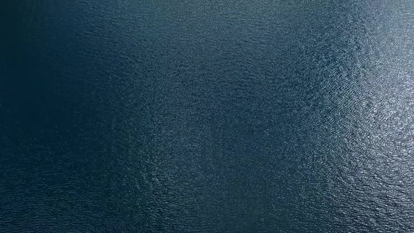 Drone pan up of Lake Lauvitel in the French Alps. It reveals the beautiful surroundings of the lake.