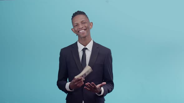 Satisfied Black Male Businessman Slams a Bundle of Dollar Bills on the Palm of Hand and Smiles in