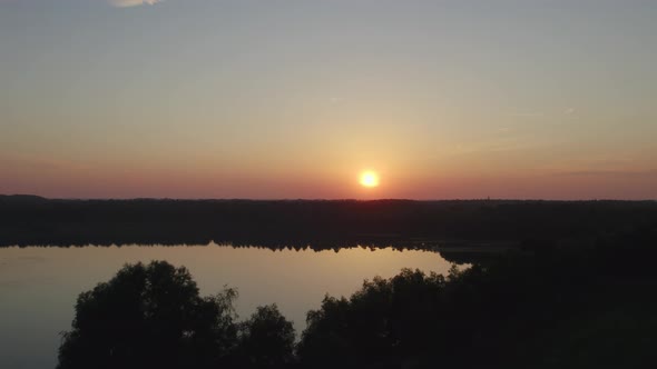 Countryside Dramatic and Colorful Sunset Flight Over a Forest Lake Aerial Shot on a Drone