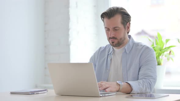 Busy Young Man Typing on Laptop in Office