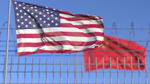 Waving Flags of the USA and China Separated By Barbed Wire