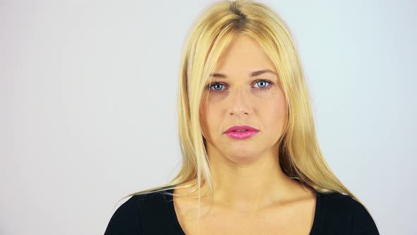 A Young Attractive Woman Looks Seriously at the Camera - Face Closeup - White Screen Studio