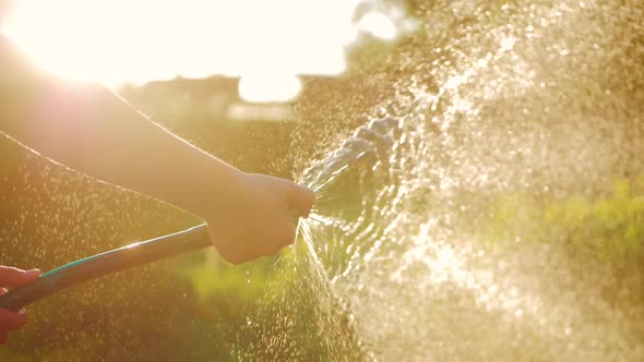 Funny Little Girl in Hat Playing with Garden Hose in Sunny Backyard. Adorable Little Girl Playing