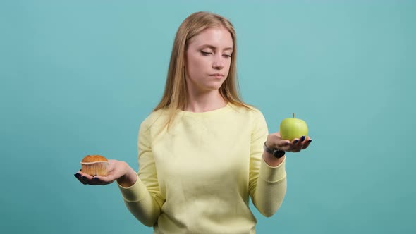 Young Woman Choosing Between Apple and Cupcake, the Girl Is Choose Apple