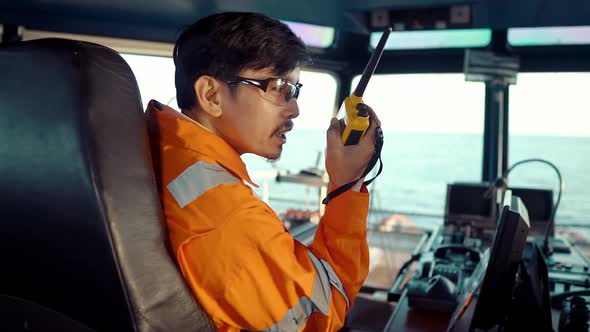 Filipino Deck Officer on Bridge of Vessel or Ship. He Is Speaking on GMDSS VHF Radio