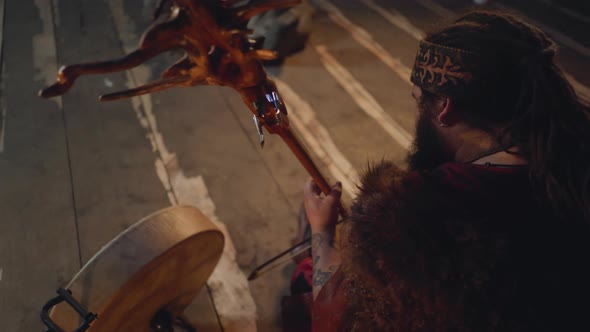 Man with Fur Plays Stylish String Instrument on Rustic Stage