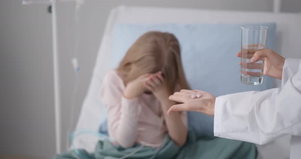 Sick Girl Patient Covering Face with Hands Refusing To Take Medicine in Hospital Ward