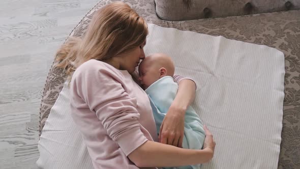 Mom and Newborn Are Lying on the Bed, Top View. Mom and Son Lie on the Bed