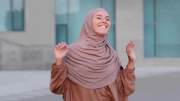 Portrait of Playful Young Arab Muslim Woman in Traditional Hijab Dancing with Shoulders Arms Moving