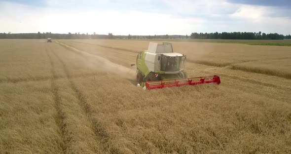 Flycam Shows Combine Taking in Grain Stalks Leaving Dust