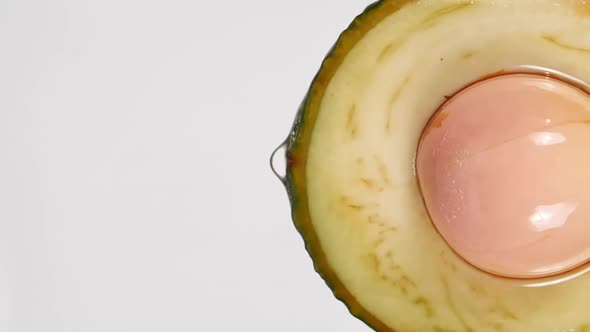 Slow Motion of Flowing the Juice and Oil Stream From Avocado Slice on White Background