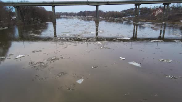 Road Bridge Over a Dim River Stream with Floating Ice Floes