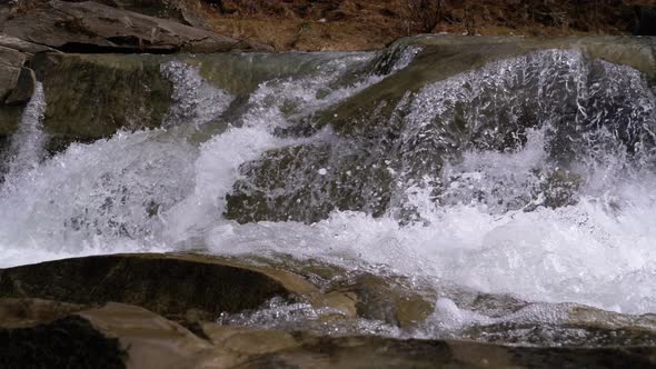 Mountain Creek and Stone Rapids with Snow. Rapid Flow of Water. Waterfall in the Winter. Slow Motion