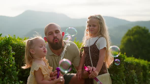 Father and Kids Blowing Soap Bubbles Outdoors