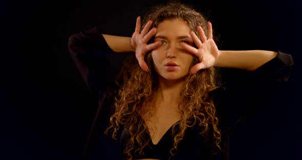 A Close-up Portrait of a Smiling Curly-haired Young Girl Who Is in the Studio on a Black Background